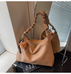 Détail du sac croissant caramel avec texture grainée et breloque ours peluche