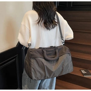 Rear view of a model carrying a charcoal and checkered travel bag on a wooden staircase