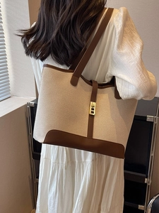 Large canvas tote bag with brown leather trim and gold buckle for commute use