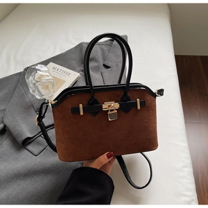 Détail du sac à main en daim marron avec cadenas doré et fines lanières en cuir noir
