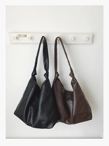 Detail view of large tote bags in black and dark coffee with tied knots and soft PU texture