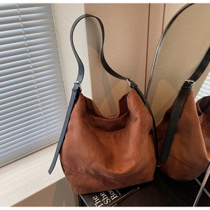 Close-up of brown suede hobo bag with adjustable black leather strap and silver buckle