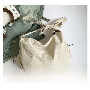 Sac bandoulière en nylon crème avec nœud d'épaule et texture plissée en vue à plat