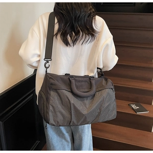 Black nylon gym bag with gray pattern showing detachable shoulder strap on model