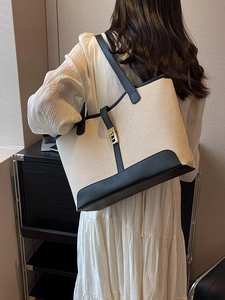 Minimalist large canvas tote bag with black leather base and straps shown on a model