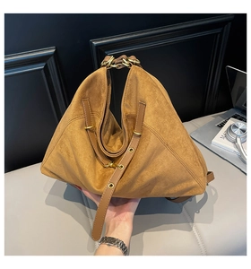 Detail of a brown suede triangle bag featuring gold hardware and modern textured finish