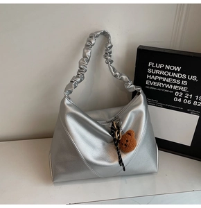 Détail du sac cabas argenté avec poignée froncée et breloque ours mignonne