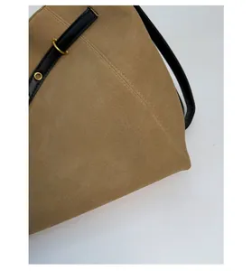 Macro detail of beige suede tote bag showing durable stitching and gold metal ring hardware