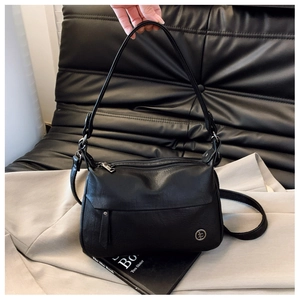 Detail of black leather square handbag featuring soft pebble grain and dual strap options