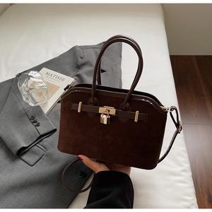 Détail du sac à main en daim marron avec fermoir rotatif doré sur fond blanc pur