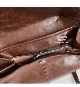 Detail view of smooth metal zipper and magnetic snap closure on brown leather backpack