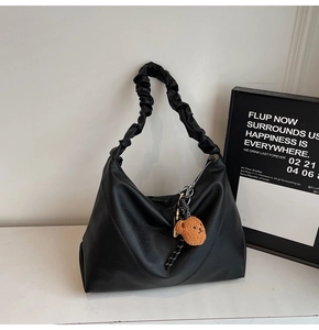 Détail du sac cabas noir avec poignée froncée et accessoire de charme en forme d'ours