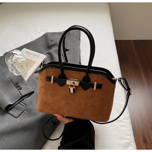 Détails d'un sac coquille en daim marron avec poignées en cuir noir et fermoir en métal doré