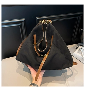 Detailed view of black suede tote bag with geometric folds and brown leather straps