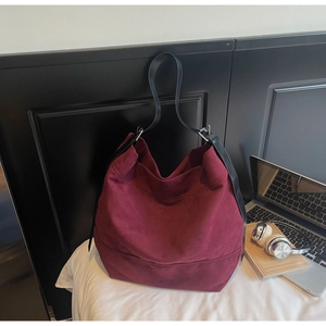 Détail d'un grand sac cabas en daim bordeaux avec bandoulière réglable en cuir noir