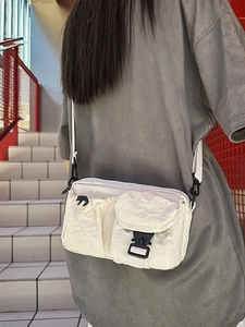 White casual nylon crossbody bag with multi-pocket design and black buckles on model