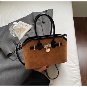 Détail du sac en daim marron avec cadenas doré, lanières en cuir noir et bandoulière
