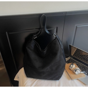 Détail du grand sac cabas noir mat avec bandoulière large dans un bureau moderne