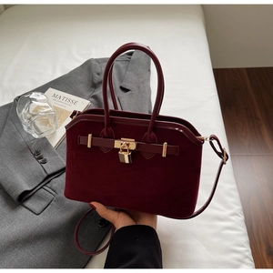 Détail du sac bordeaux mat avec fermoir doré et finitions de bandoulière vintage