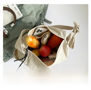 Intérieur spacieux du sac à bandoulière en nylon beige montrant les rangements quotidiens