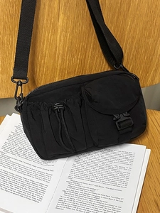 Fashionable black nylon crossbody bag with multi-pocket design on a wooden chair