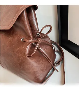 Detail of vintage brown wax leather backpack with drawstring bow and metal eyelets