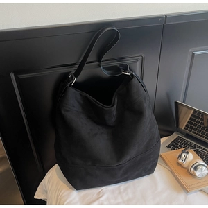 Macro shot of large black suede tote bag with adjustable strap and metallic hardware