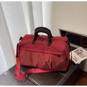 Deep red large capacity travel bag with red and white checkered detail on a bench