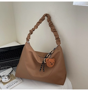 Détail du sac cabas en cuir marron avec bandoulière à volants et breloque ours en peluche
