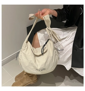 Détail du grand sac bandoulière blanc crème avec cordons latéraux et sangle réglable