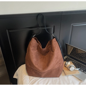 Vue détaillée du sac hobo en daim marron avec bandoulière en cuir noir et texture douce