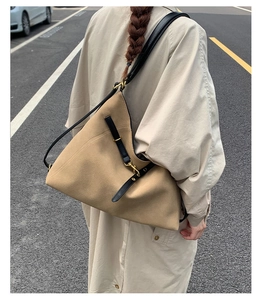 Close-up of khaki tote bag with black leather straps and gold metal hardware detail