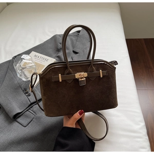 Vue détaillée du sac coquille en daim marron foncé avec son fermoir pivotant en métal vintage