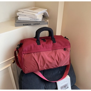 Detail of burgundy fitness bag featuring white checkered pattern and wide shoulder strap