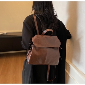 Detail of vintage dark brown leather backpack showing magnetic flap and side drawstring cord