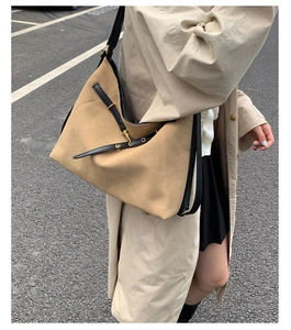 Detail of camel frosted suede tote bag with black leather straps and gold buckle