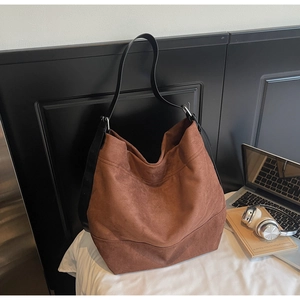 Detail of a large brown suede tote bag with adjustable black leather shoulder strap