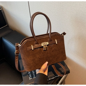 Vue détaillée du sac coquille en daim marron foncé avec boucle dorée et poignée en cuir