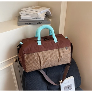 Close-up of brown gym bag with plaid pattern, mint green handles and leather branding detail