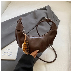 Détail du sac bandoulière marron foncé en forme de corne avec perles en bois décoratives