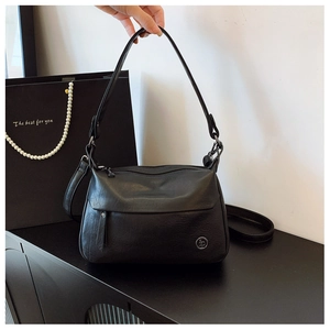 Detail of black vintage square bag with metal logo, zipper closure and dual straps