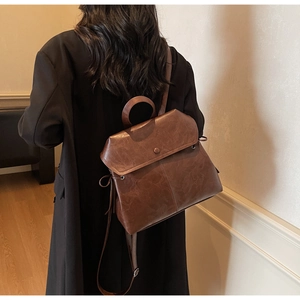 Close-up of brown vintage leather backpack showing texture and round handle on model