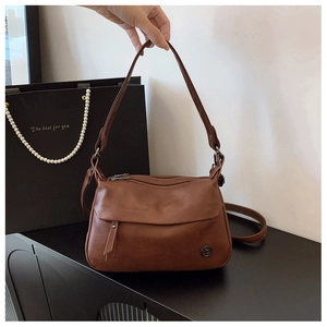 Detail of vintage brown leather handbag with multi-zipper layers and rivet hardware