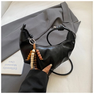 Détail du sac croissant noir avec perles en bois et bandoulière à nœuds design