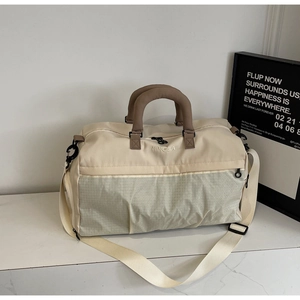 Detail of spacious travel duffel bag with grey plaid base and brown handles on marble top