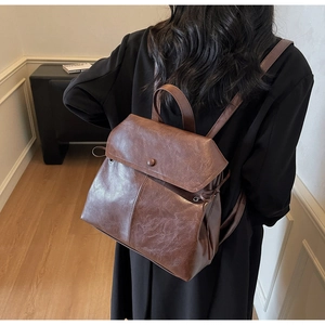 Detailed back view of a brown vintage leather backpack with drawstring and flap closure