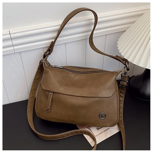 Close-up of vintage brown leather handbag with multiple zippers and round metal logo