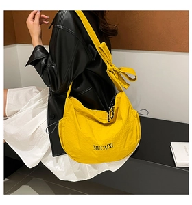 Détail du sac à bandoulière jaune en forme de ravioli avec nœud papillon et logo MUCAIXI