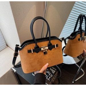 Détail du sac en daim avec lanières en cuir et fermoir doré sur fond miroir