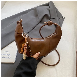 Détail du sac demi-lune caramel avec bandoulière torsadée et pendentif en perles ethniques